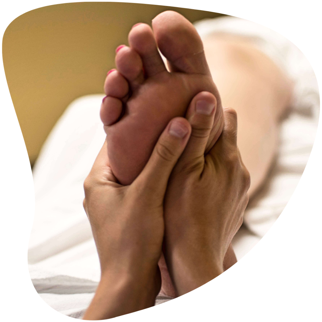Mains  d'une réflexologue qui réalisent un massage réflexologique sur un pied.
